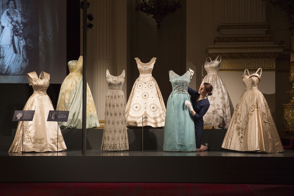 A display of evening wear from Fashioning a Reign: 90 Years of Style from The Queen√¢¬Ä¬ôs Wardrobe on show at Buckingham Palace. Images for use only in connection with the exhibition Fashioning a Reign: 90 Years of Style from The Queen's Wardrobe at the Summer Opening of Buckingham Palace, 23 July - 2 October 2016. Images must not be archived or sold-on. Royal Collection Trust / √Ç¬© Her Majesty Queen Elizabeth II 2016. Single use only; not to be archived or passed on to third parties.