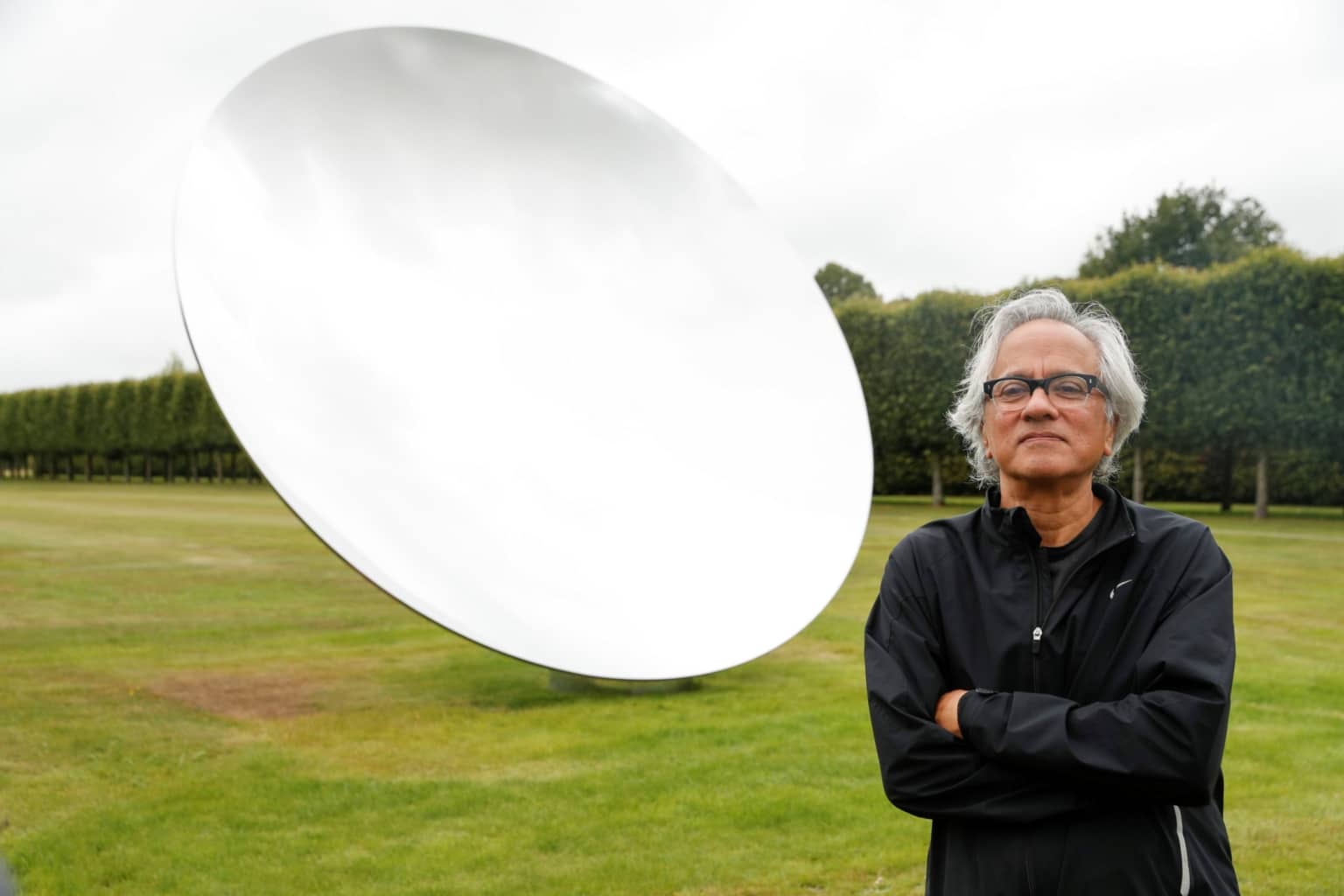 British-Indian artist Anish Kapoor poses with his sculpture in the gardens at Houghton Hall in Norfolk